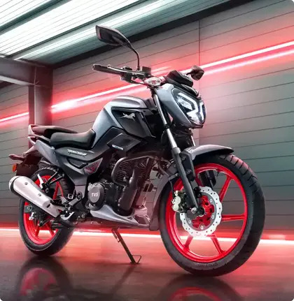 TVS Raider 125 2025 model in black with red alloy wheels displayed under neon lights.