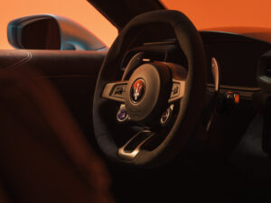 Close-up of the Maserati MC20 Cielo Coupe steering wheel featuring the trident logo, carbon-fiber finish, and mounted drive control buttons.